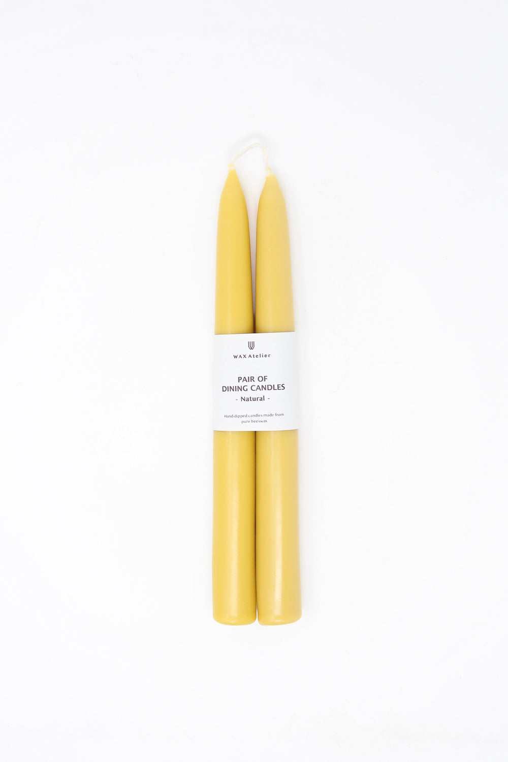 A pair of yellow Wax Atelier Beeswax Dining Candles in Natural against a white background.