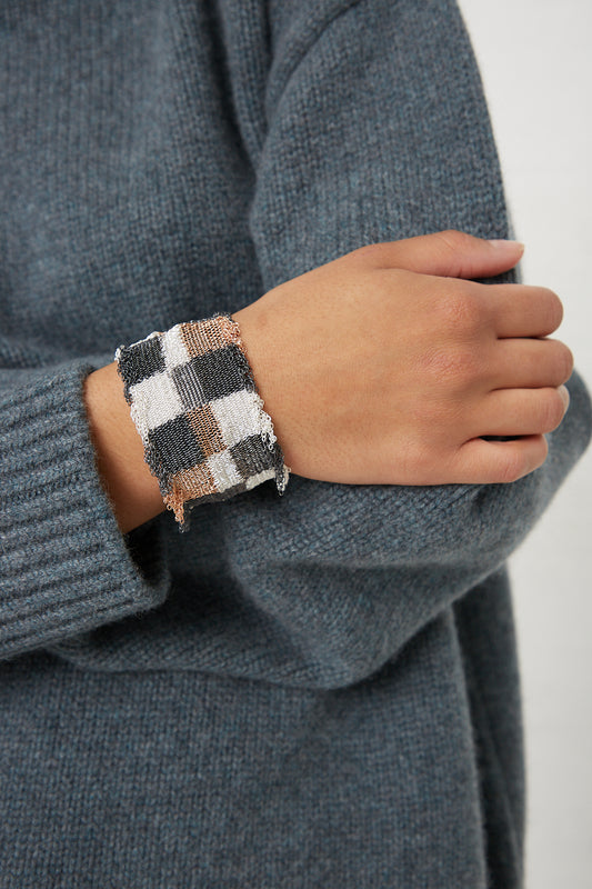 A woman wearing a sweater with a checkered cuff and a Stephanie Schneider Rose Gold Plated and Silk Silver Bracelet.