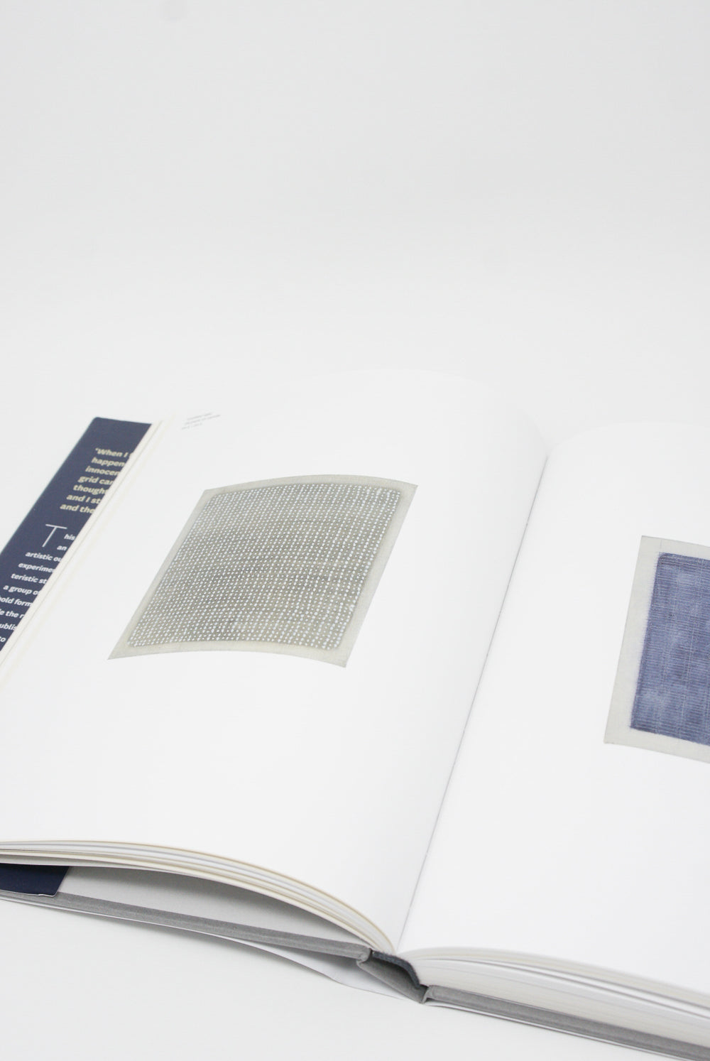 An open book featuring a retrospective exhibition on Agnes Martin, with text and images on a white surface. Product: Artbook/D.A.P.'s Agnes Martin: Illustrated Monograph.
