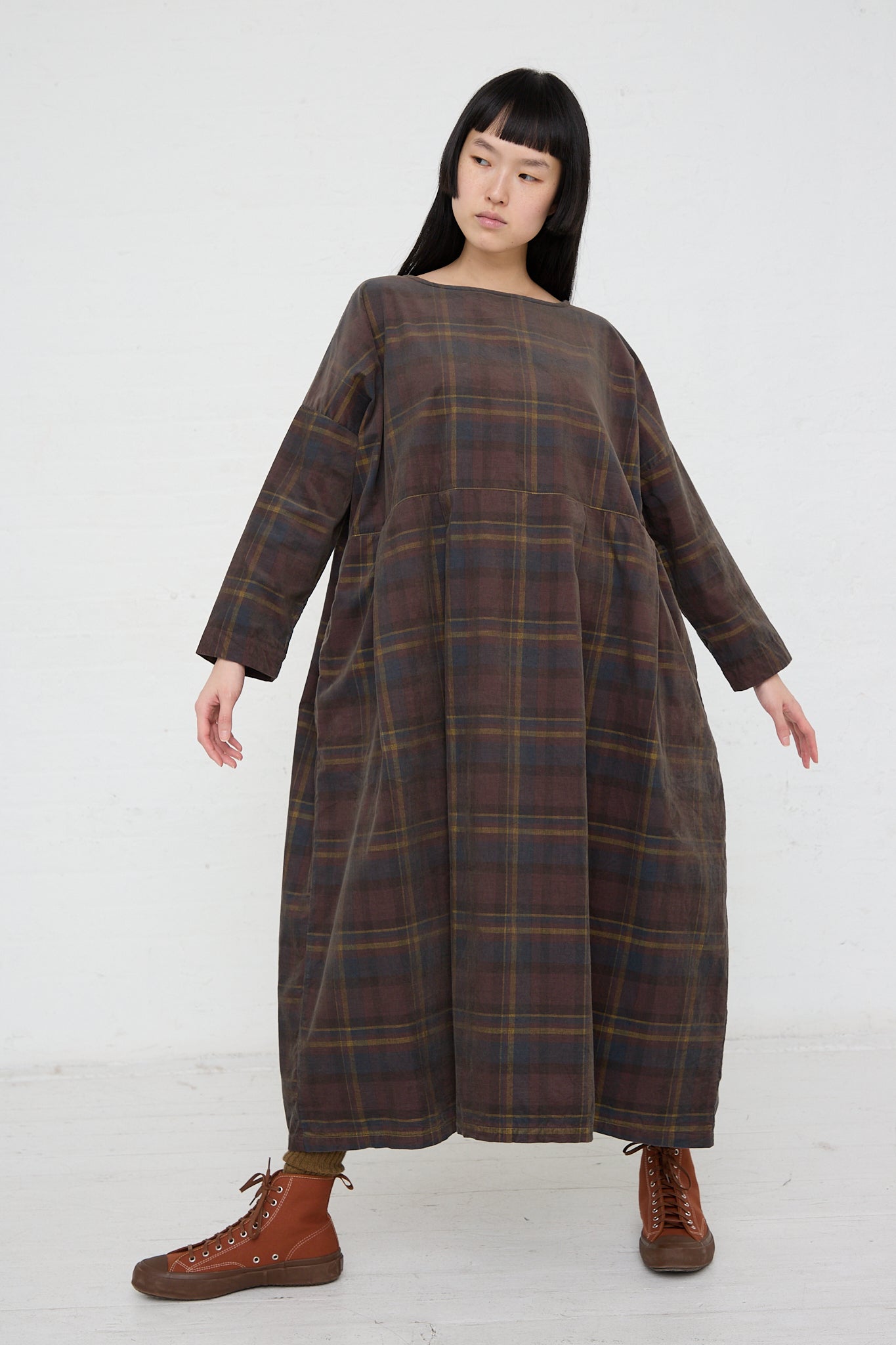 A woman wearing a relaxed fit Ichi brown plaid dress made of woven cotton fabric.