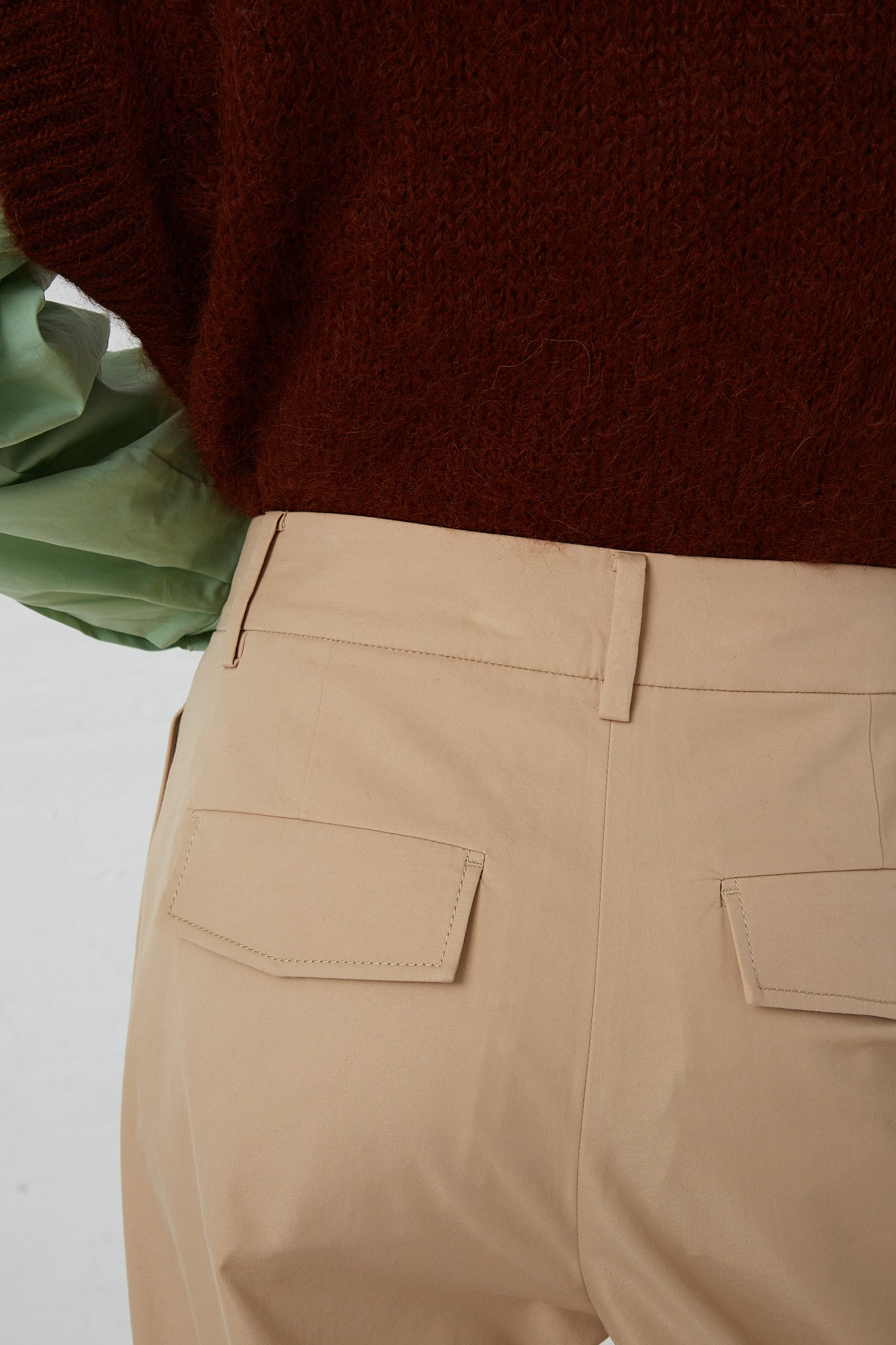 The back view of a woman wearing Rejina Pyo's Cotton Blend Macie Trouser in Tan. Up close detail of back pockets.