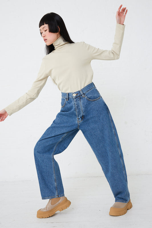 A woman in a turtle neck top and wide leg jeans made from Jesse Kamm's Japanese Denim California Wide in Cowboy Blue, showcasing a minimalist wardrobe aesthetic.