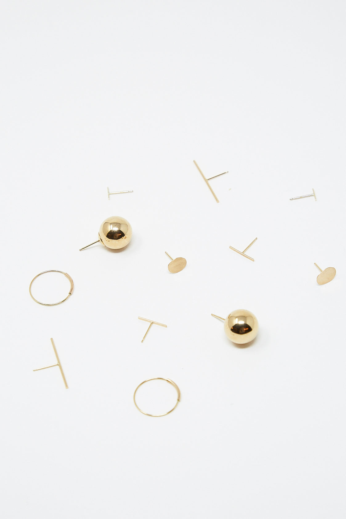 A collection of Kathleen Whitaker Stick Stud 1" Single Earrings in 14K Yellow Gold on a white surface.
