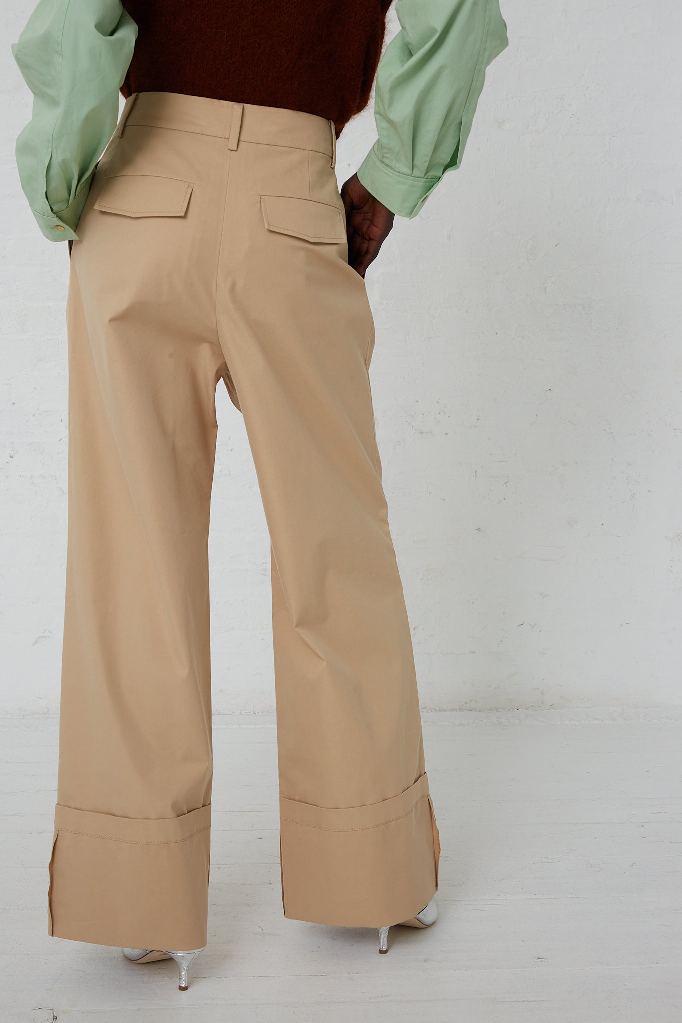 The back view of a woman wearing Rejina Pyo's Cotton Blend Macie Trouser in Tan, beige wide leg double pleat pants.