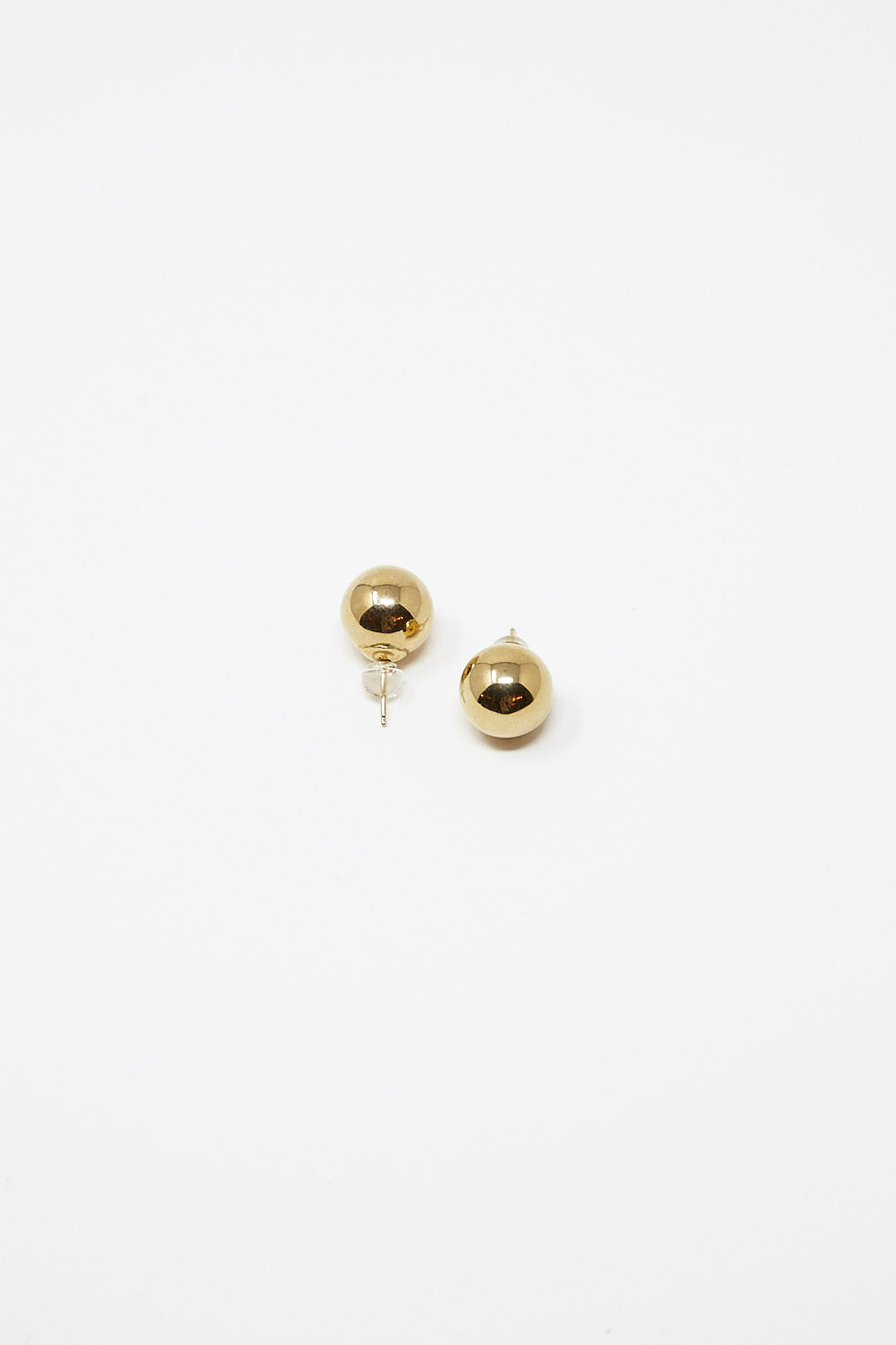 A pair of Kathleen Whitaker Sphere Stud Large 12mm Single Earrings in 14K Yellow Gold on a white surface in Los Angeles.