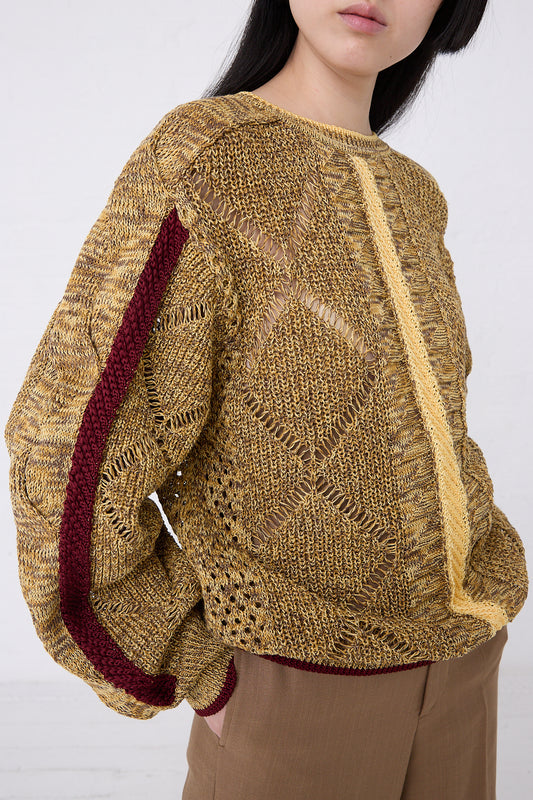 Side view of a woman modeling a textured Mesh Knit Pullover in Yellow with burgundy details, standing against a white background from TOGA ARCHIVES.