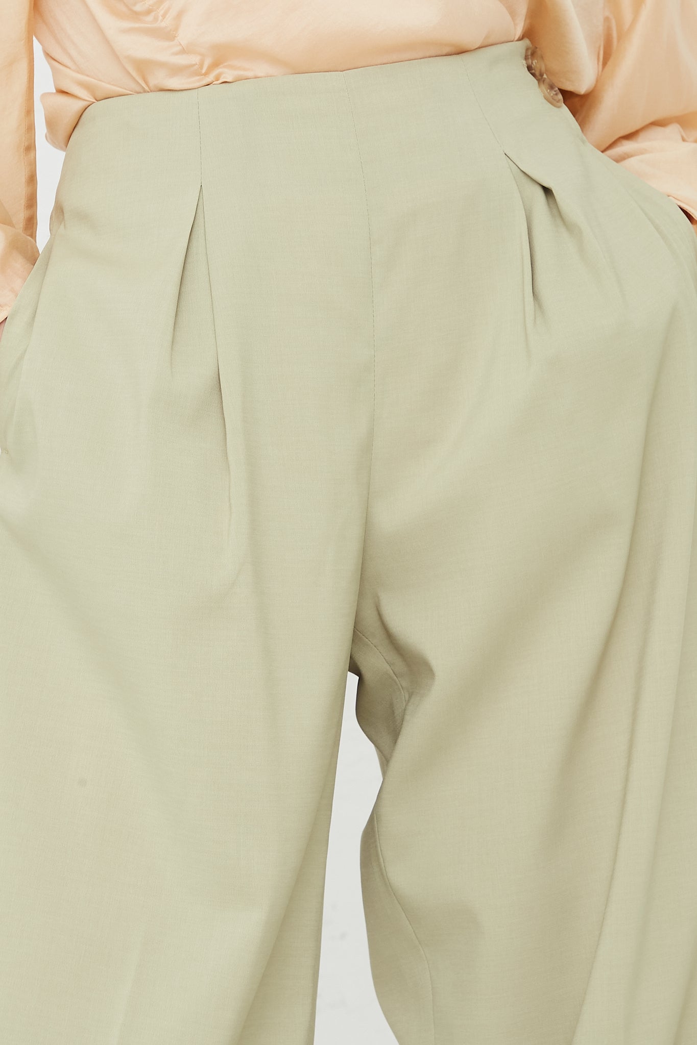 The front view of a woman in Rejina Pyo's Reine Trouser in Sage made from a polyester silk blend fabric. Up close view.