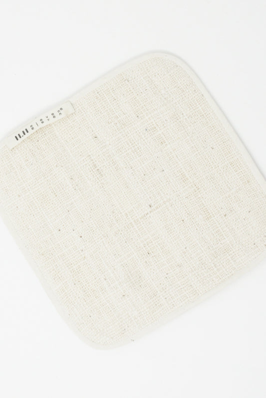 Ecru square 100% cotton fabric swatch with printed label on white background.