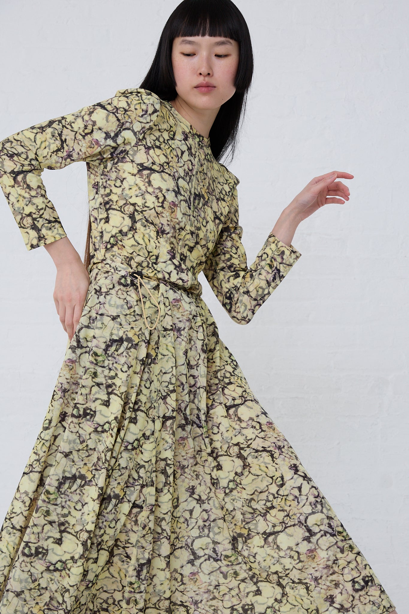 Woman in a flowing, long-sleeve TOGA ARCHIVES Tricot Print Dress in Yellow posing against a white background.