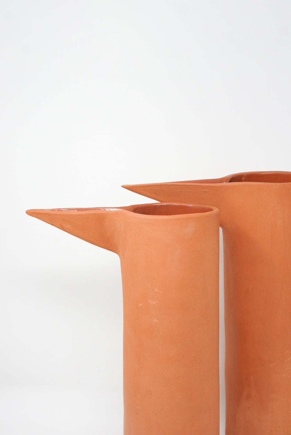 Two Beakers in Terracotta II with elongated spouts on a white background by Paula Greif.