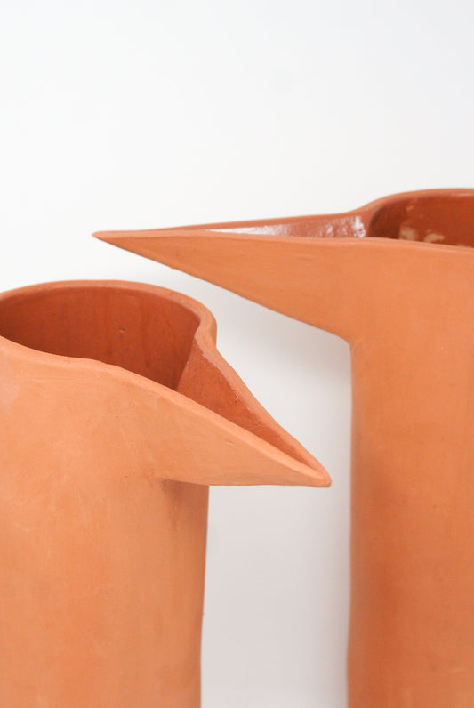 Two Beaker in Terracotta II handmade by Paula Greif, with spouts, positioned close to each other against a plain background.