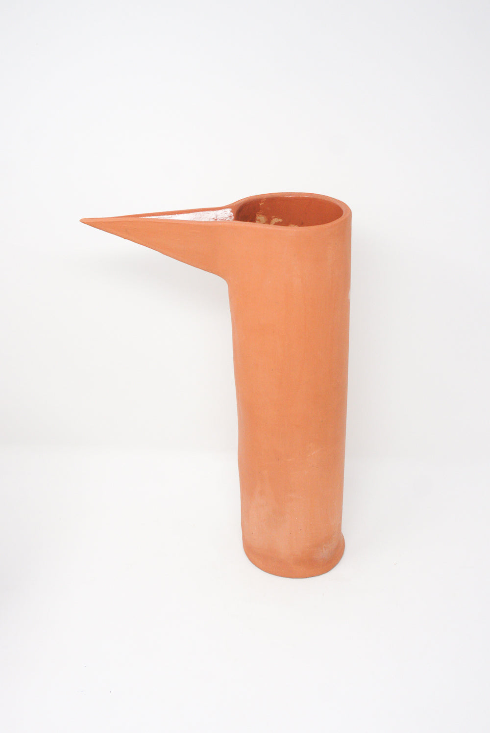 Handmade Beaker in Terracotta II with a long spout on a white background by Paula Greif.