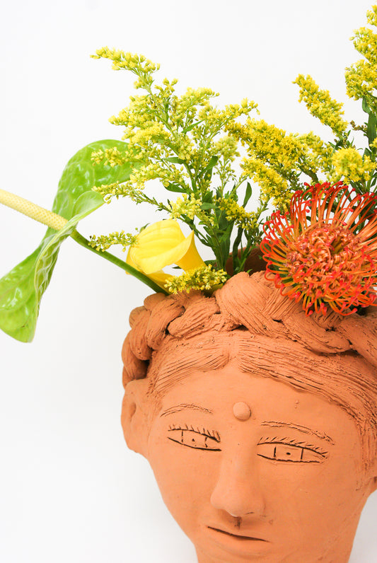 Large Head Planter in Terracotta from Travel Find, filled with a variety of flowers and foliage.