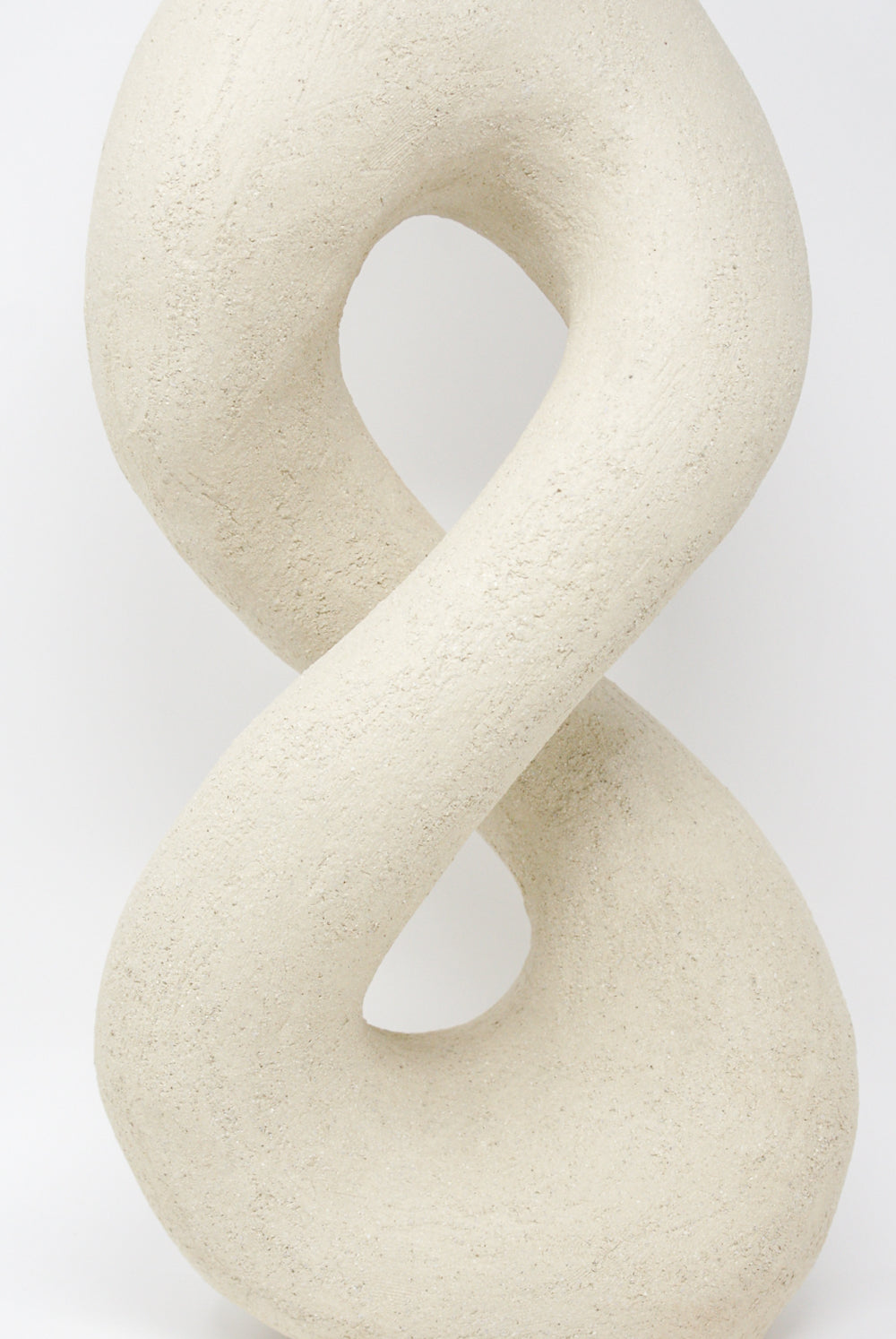 A beige, smooth-textured hand-built vessel from Lost Quarry, resembling a twisted figure-eight loop.