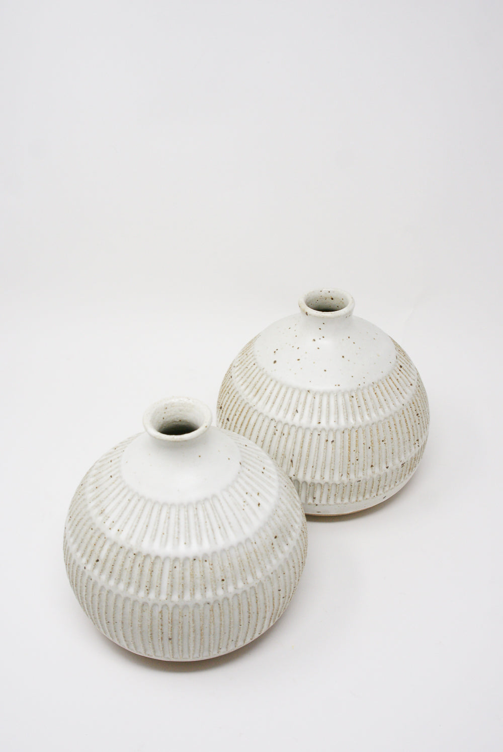 Two white ceramic vases with textured patterns on a plain background, including one Mt. Washington 6" Tulip Vase in White.