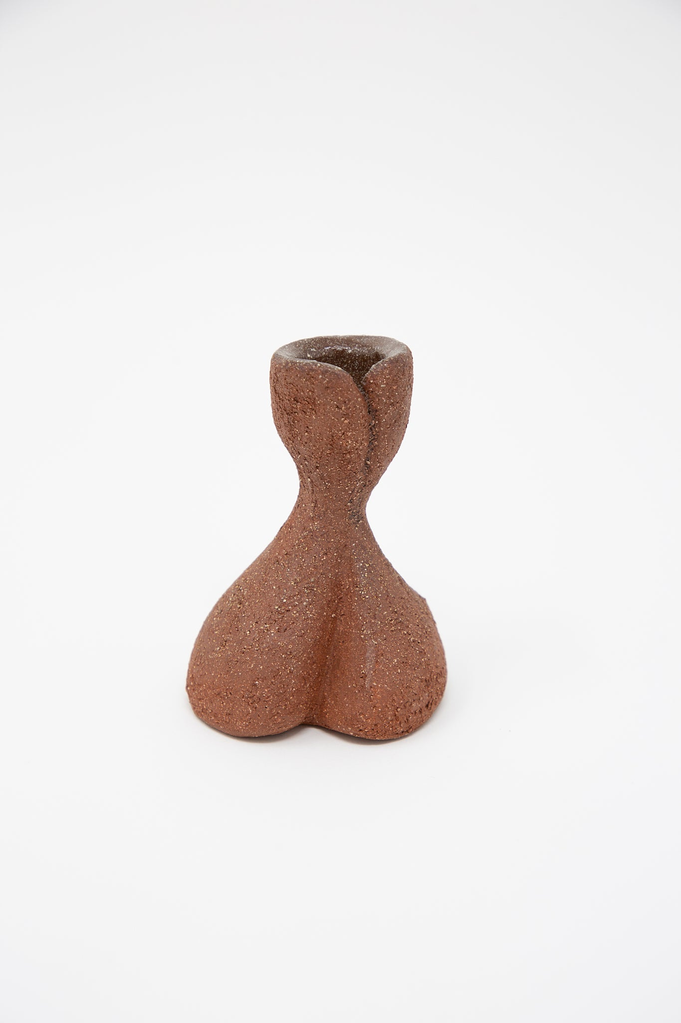 A petite, uniquely shaped candlestick made from reddish-brown terracotta sculpture clay by Lost Quarry stands on a plain white background. The handcrafted piece showcases a handmade design that reflects exceptional artistry and meticulous attention to detail.