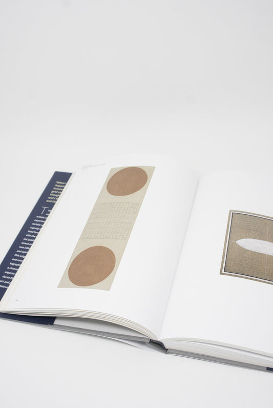 An open book featuring circular design elements inspired by Agnes Martin's art history on a white background, with a ruler placed to the side for scale, showcasing the Agnes Martin: Illustrated Monograph from Artbook/D.A.P.