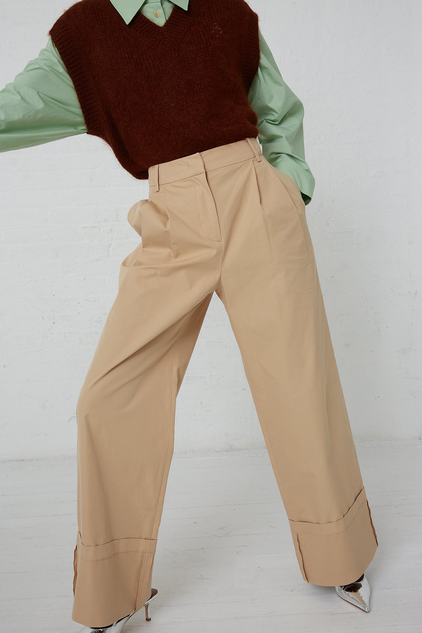 A woman in a Rejina Pyo Macie Trouser in Tan and Rejina Pyo cotton blend tan pants. Front view. Model's arm raised.