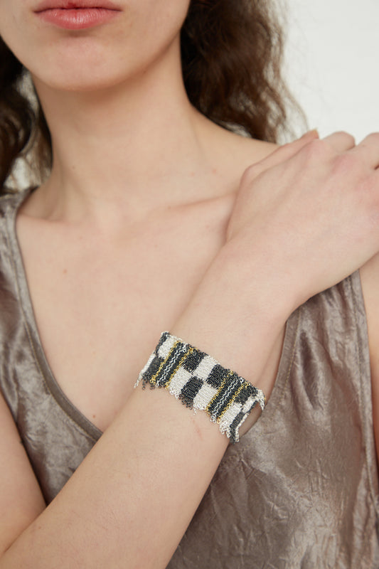 A woman wearing a Stephanie Schneider Sterling Silver Oxidized Bracelet in Gold Plated and Silk adorned with a graphic chain design.
