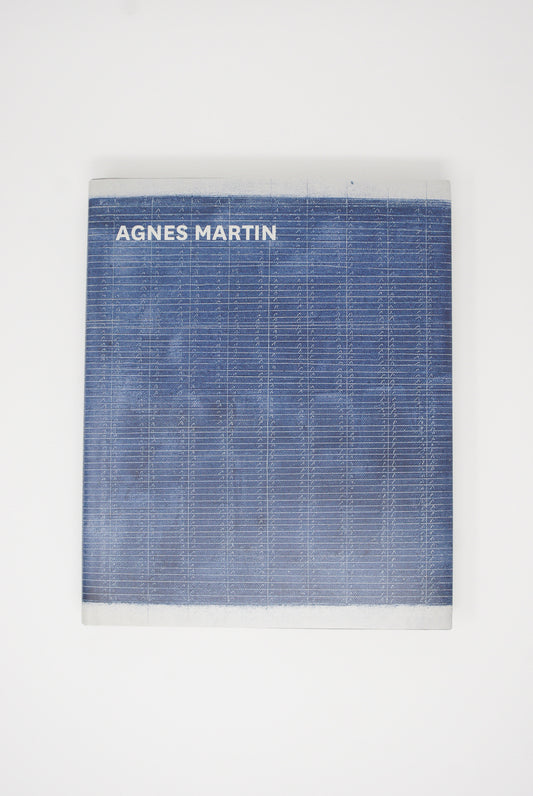 Book with "Agnes Martin: Illustrated Monograph" title on a white background with a blue textured cover design by Artbook/D.A.P.