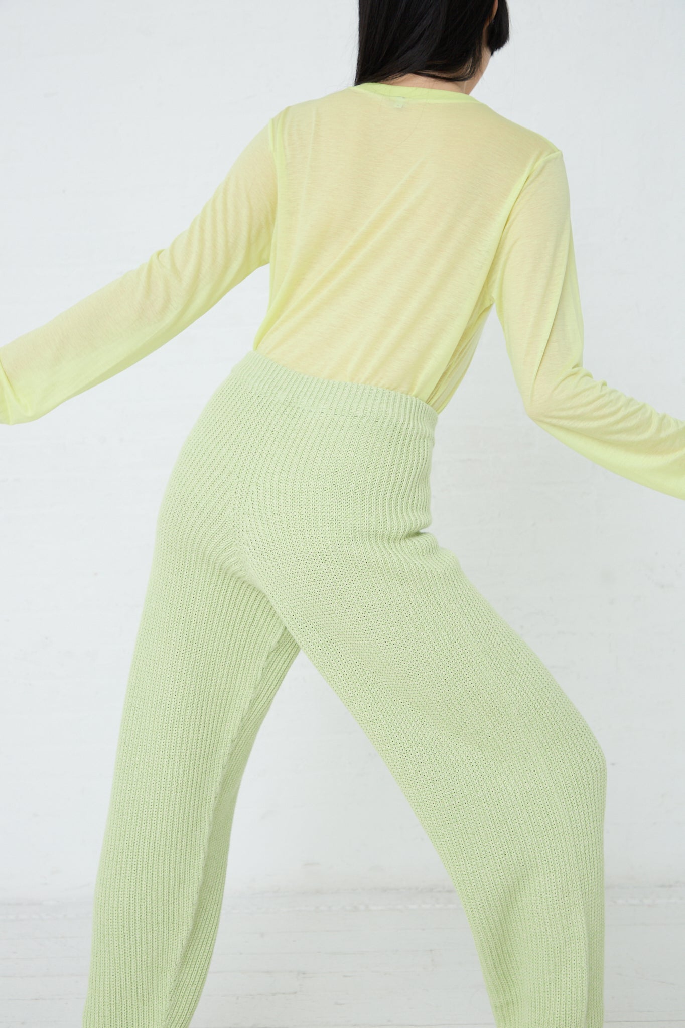 A woman wearing Baserange's Cotton Dodd Pant in Mimosa, sustainably produced green pants.
