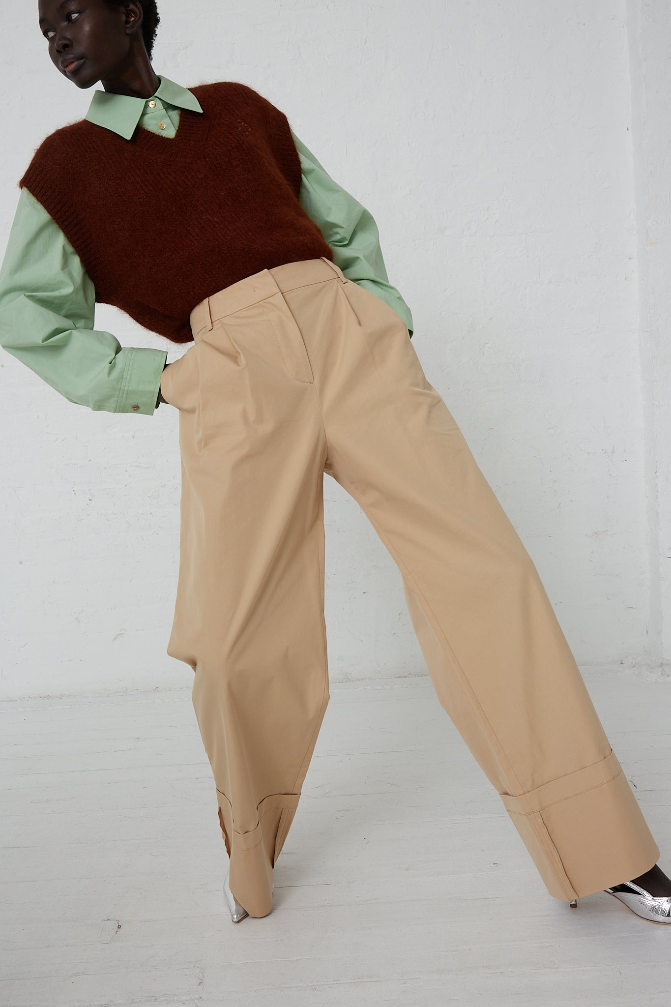 A woman in a brown sweater and beige pants wearing Rejina Pyo's Cotton Blend Macie Trouser in Tan. Model is leaning backwards.