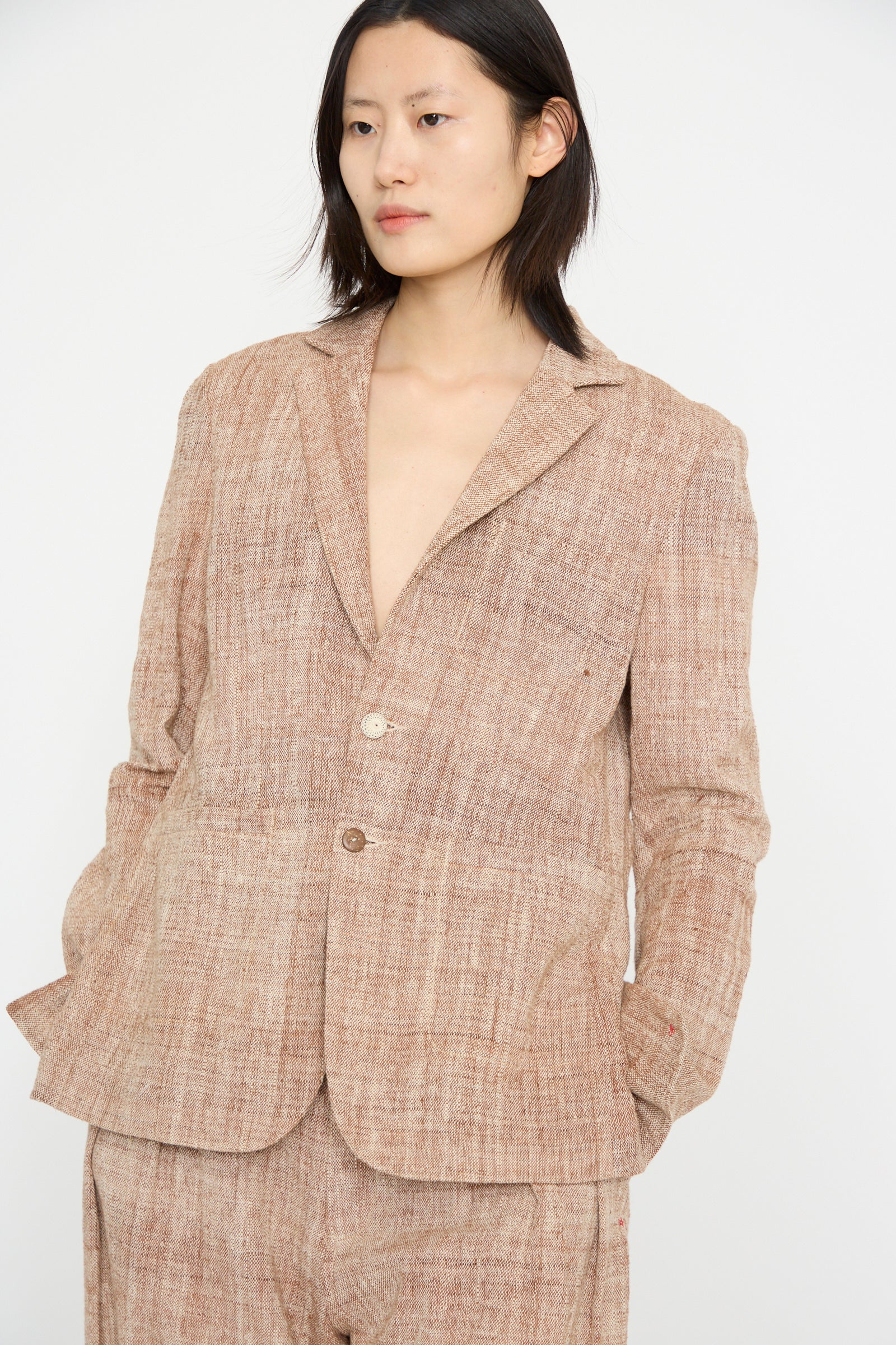 A person in 11.11's Cotton Blazer in Burnt Umber, featuring a relaxed fit and notched collar, poses against a plain white background with an air of sophistication.