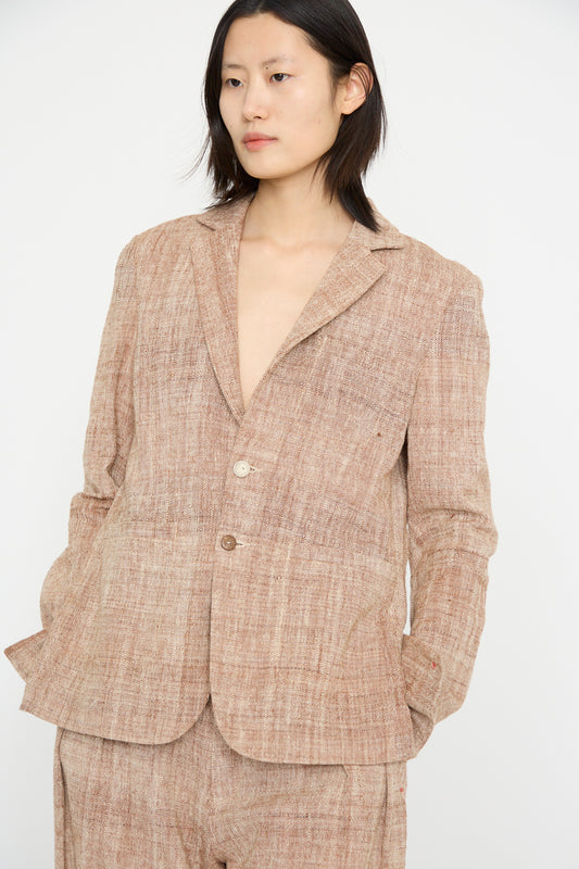 A person in 11.11's Cotton Blazer in Burnt Umber, featuring a relaxed fit and notched collar, poses against a plain white background with hands in their pockets.