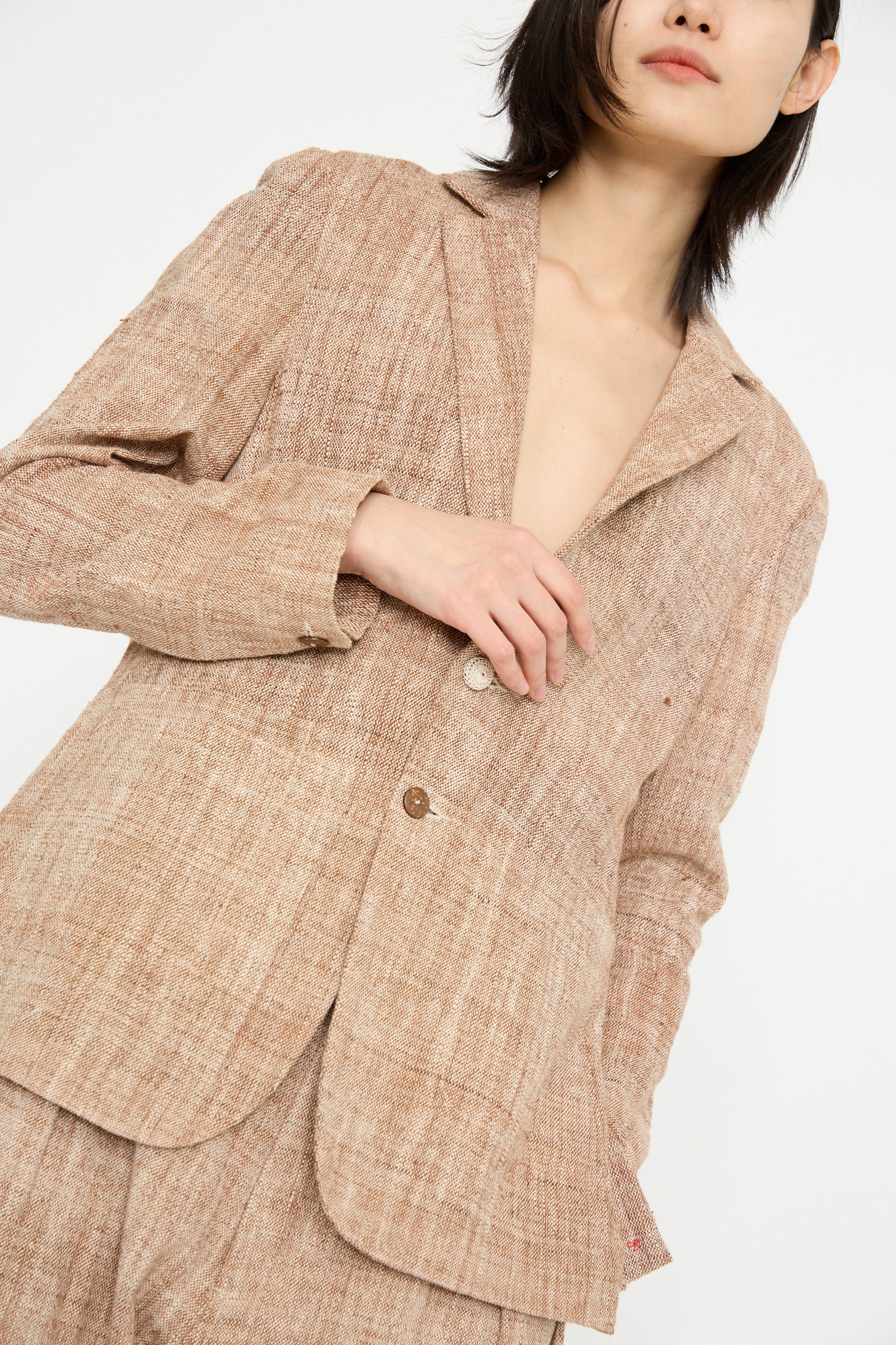 A person models the 11.11 Cotton Blazer in Burnt Umber, featuring a relaxed fit and notched collar, against a plain white backdrop.