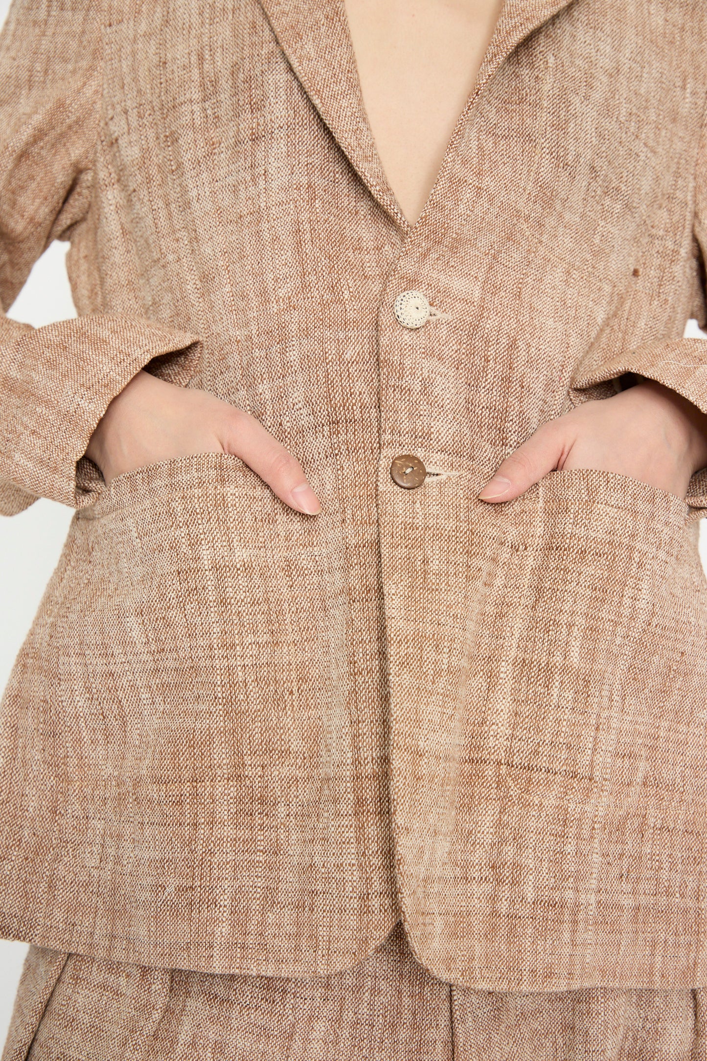 A person wearing an 11.11 Cotton Blazer in Burnt Umber with both hands in the pockets highlights its relaxed fit, two beige buttons, and a notched collar.