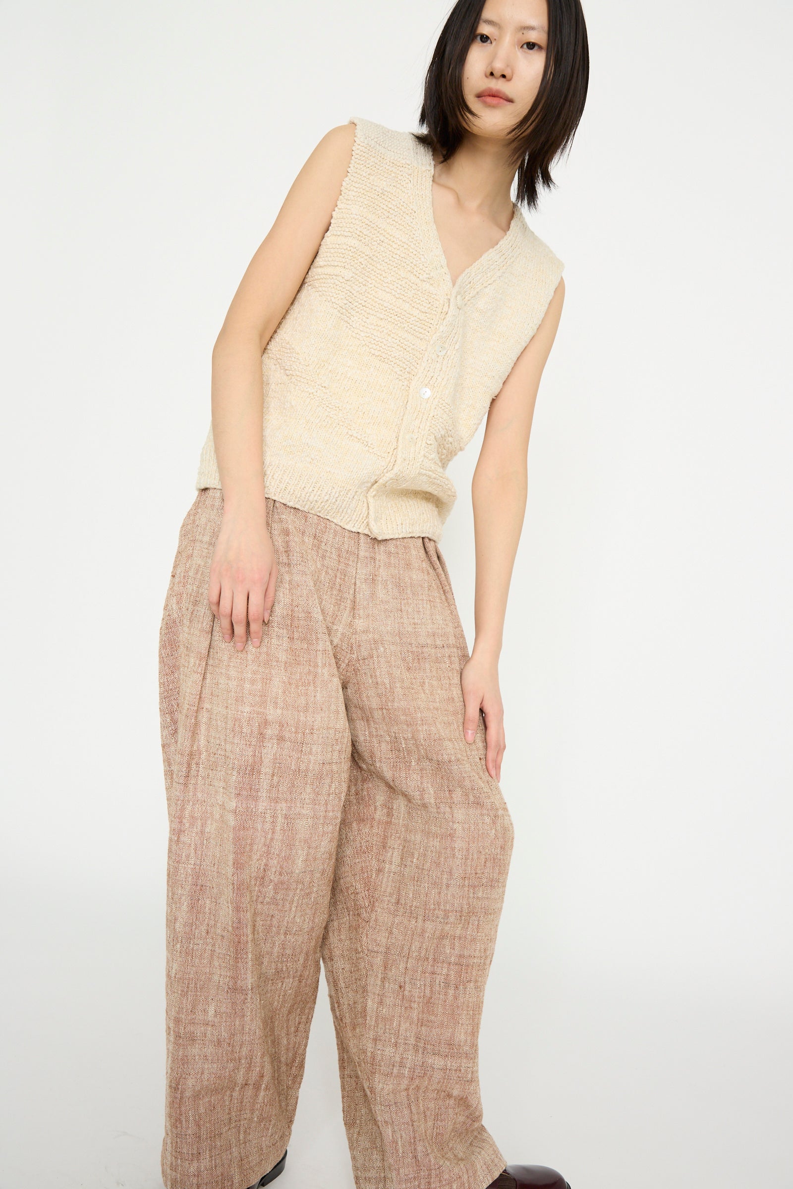 A person models the 11.11 Oro Vest in Ecru and brown loose-fitting pants, set against a neutral background.