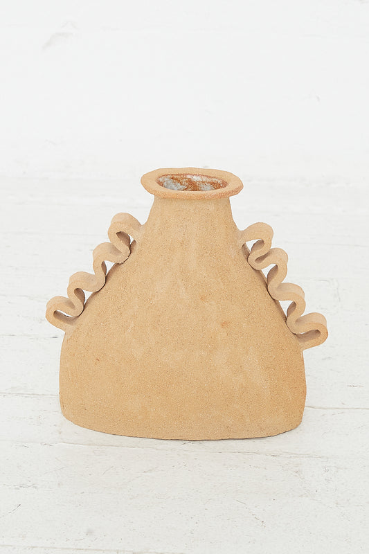 An Amphora Soleil in Raw Sunny Brown Clay vase resting on a white floor by Clandestine.