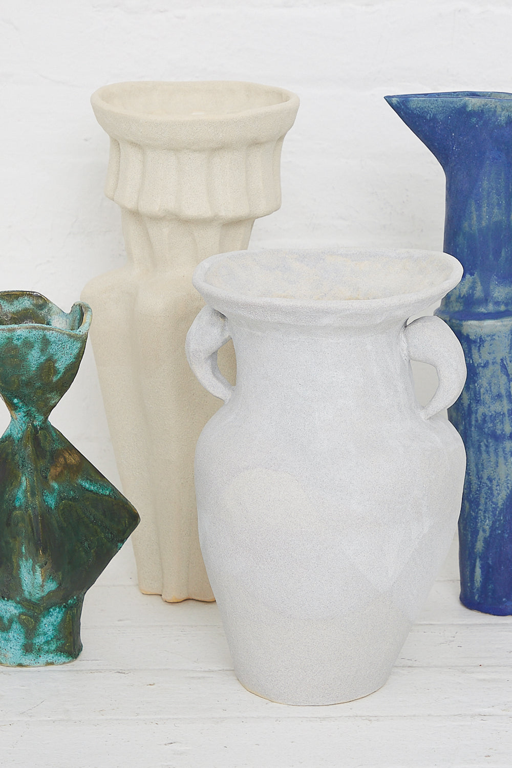 A group of ANK Ceramics Column Vessel in White vases with a white glaze on a white table.