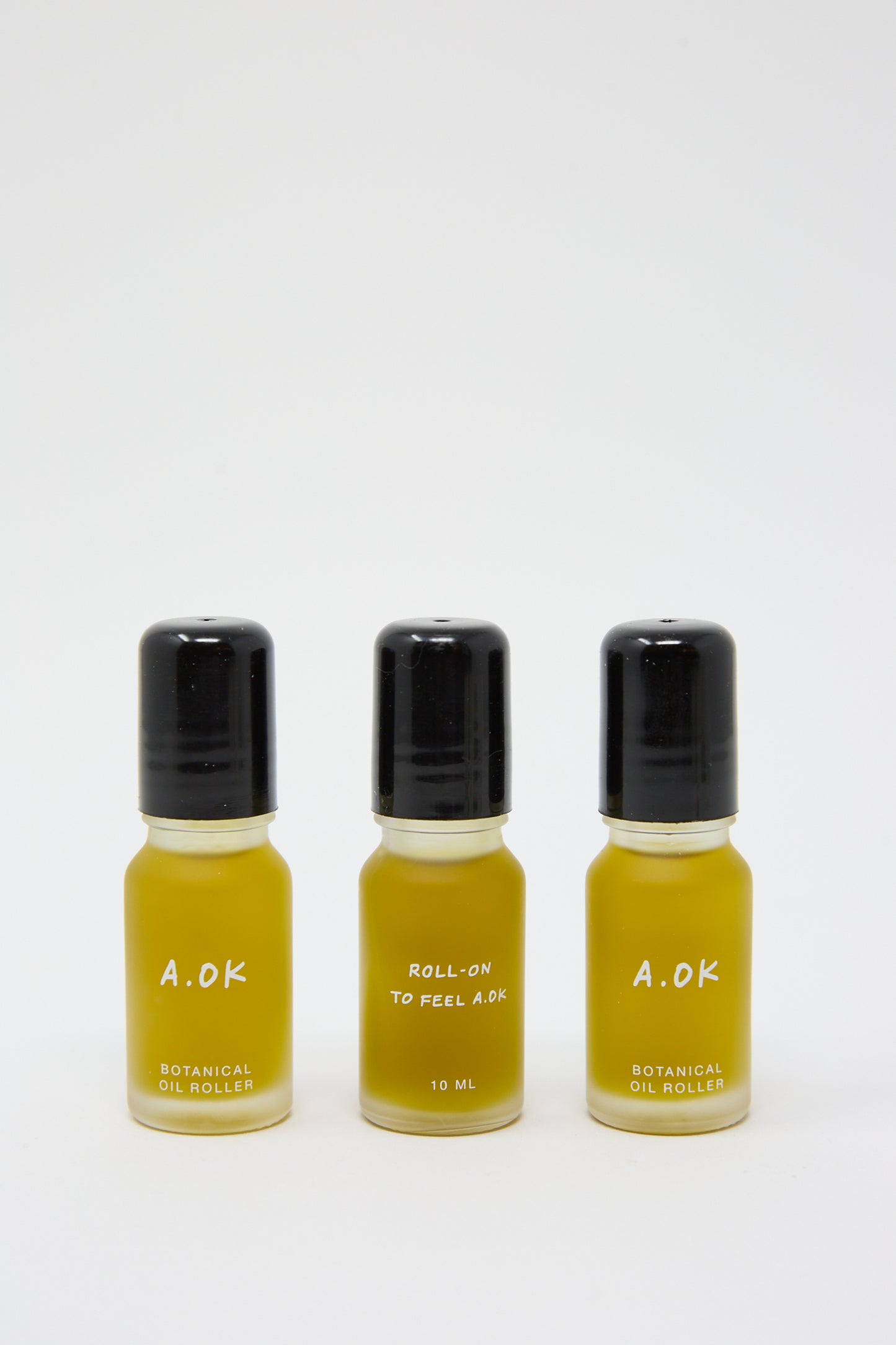 Three small bottles of Botanical Oil Roller labeled "A.OK" are aligned in a row. The middle bottle reads "Roll-on to feel A.OK," indicating a volume of 10 ml and featuring the invigorating scent of blood orange. These travel-friendly rollers are perfect for on-the-go tranquility.