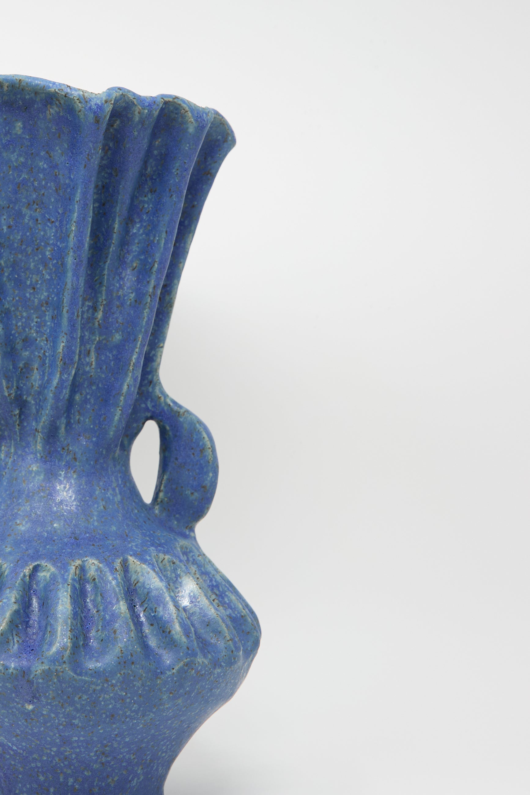 Close-up of the Pleat Vase with Handles in Blue by ANK Ceramics, showcasing its textured stoneware and rich blue glaze with fluted detailing, set against a plain light background.