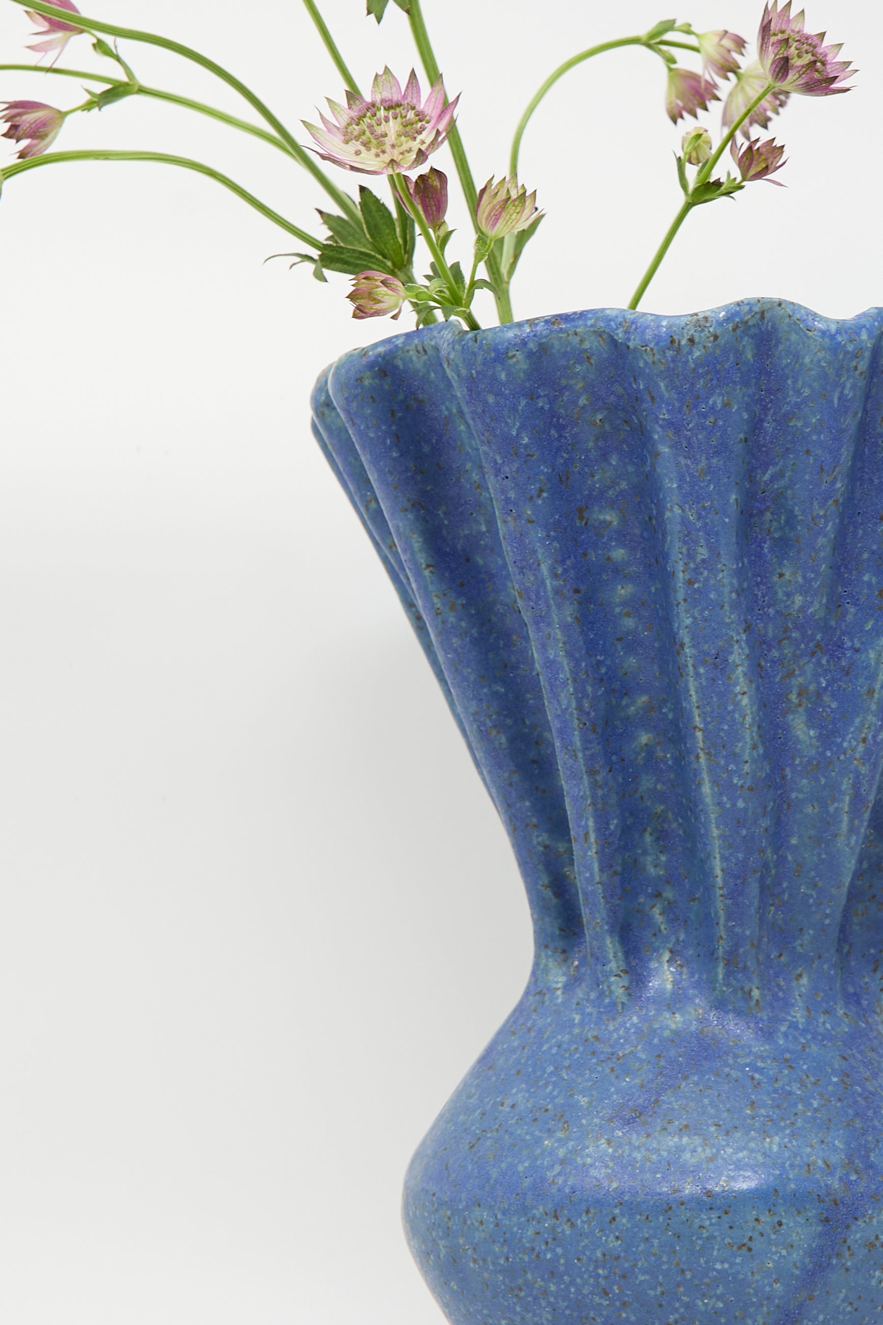 ANK Ceramics' Pleat Vase in Blue, featuring a fluted design adorned with pink flowers on a light background.