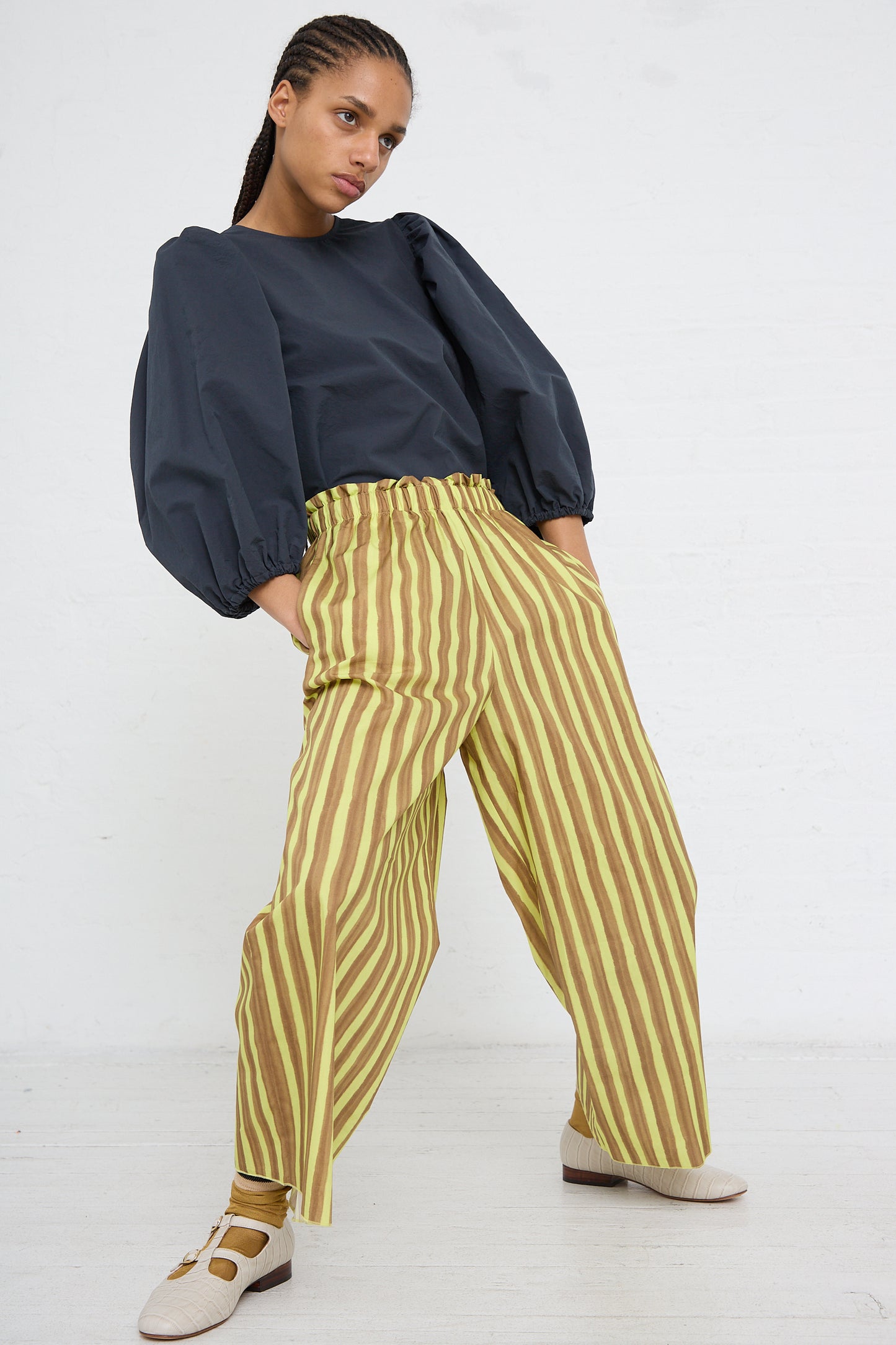 Woman posing in a dark blouse and AVN Easy Pant in Brown and Yellow Stripes.