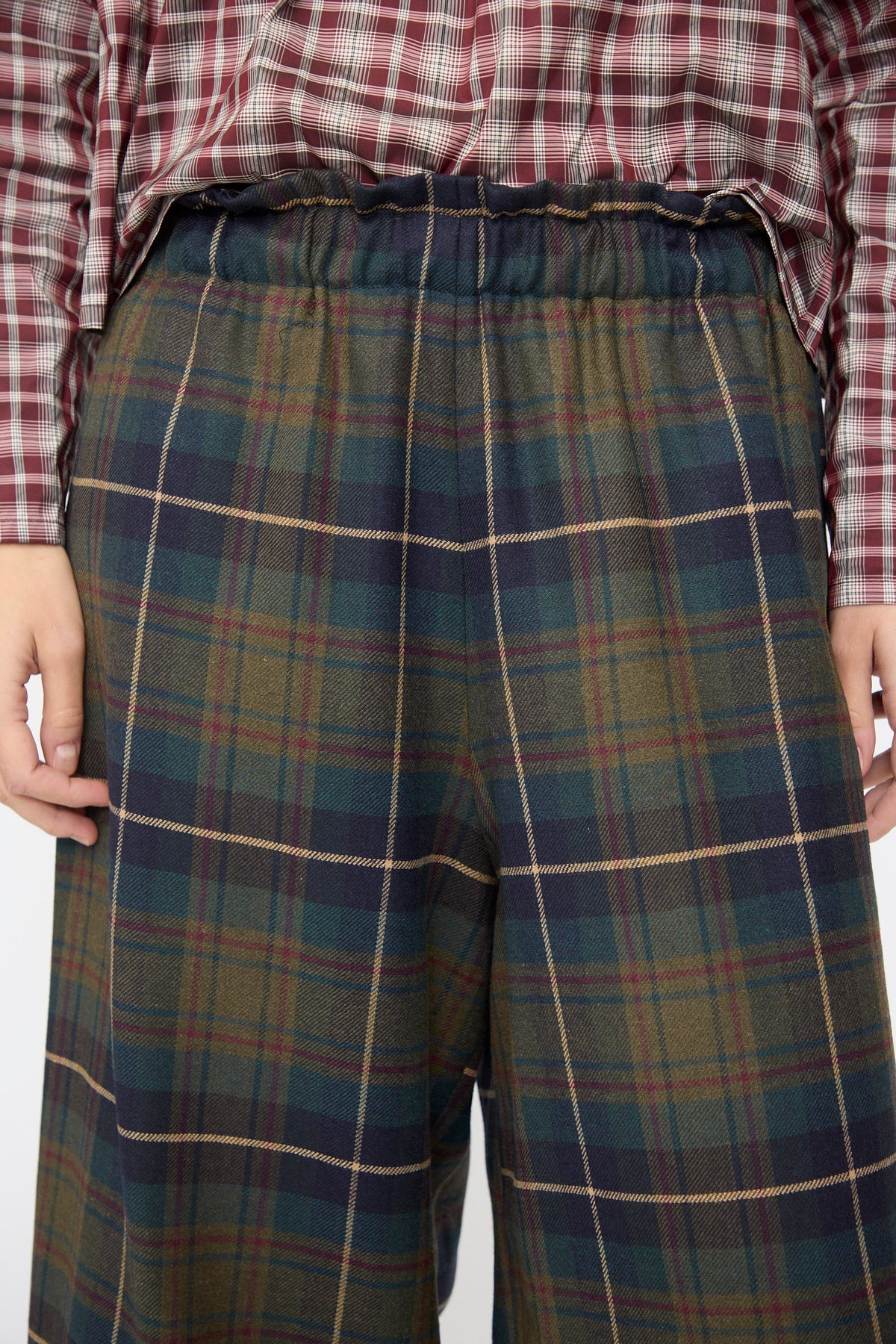 AVN Easy Pants in Military Check: wide-leg wool pants in a dark green, blue, and red plaid pattern with an elasticated waistband.