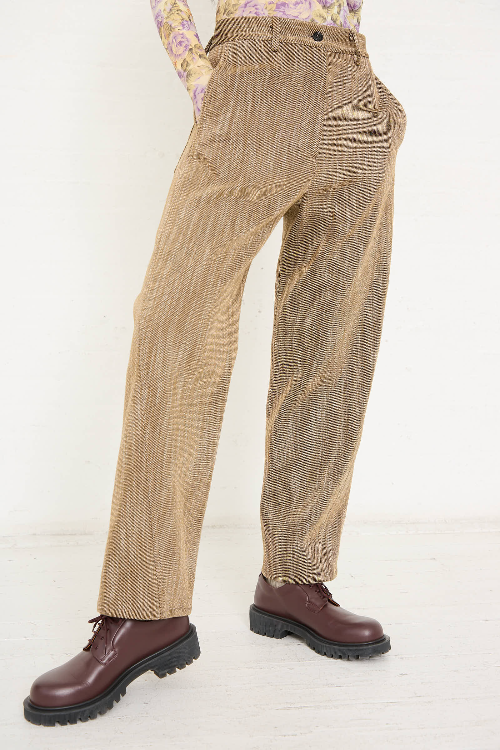 Person wearing **AVN Iris Pant in Beige** with side slash pockets, a floral printed top, and brown leather shoes, standing against a white background.