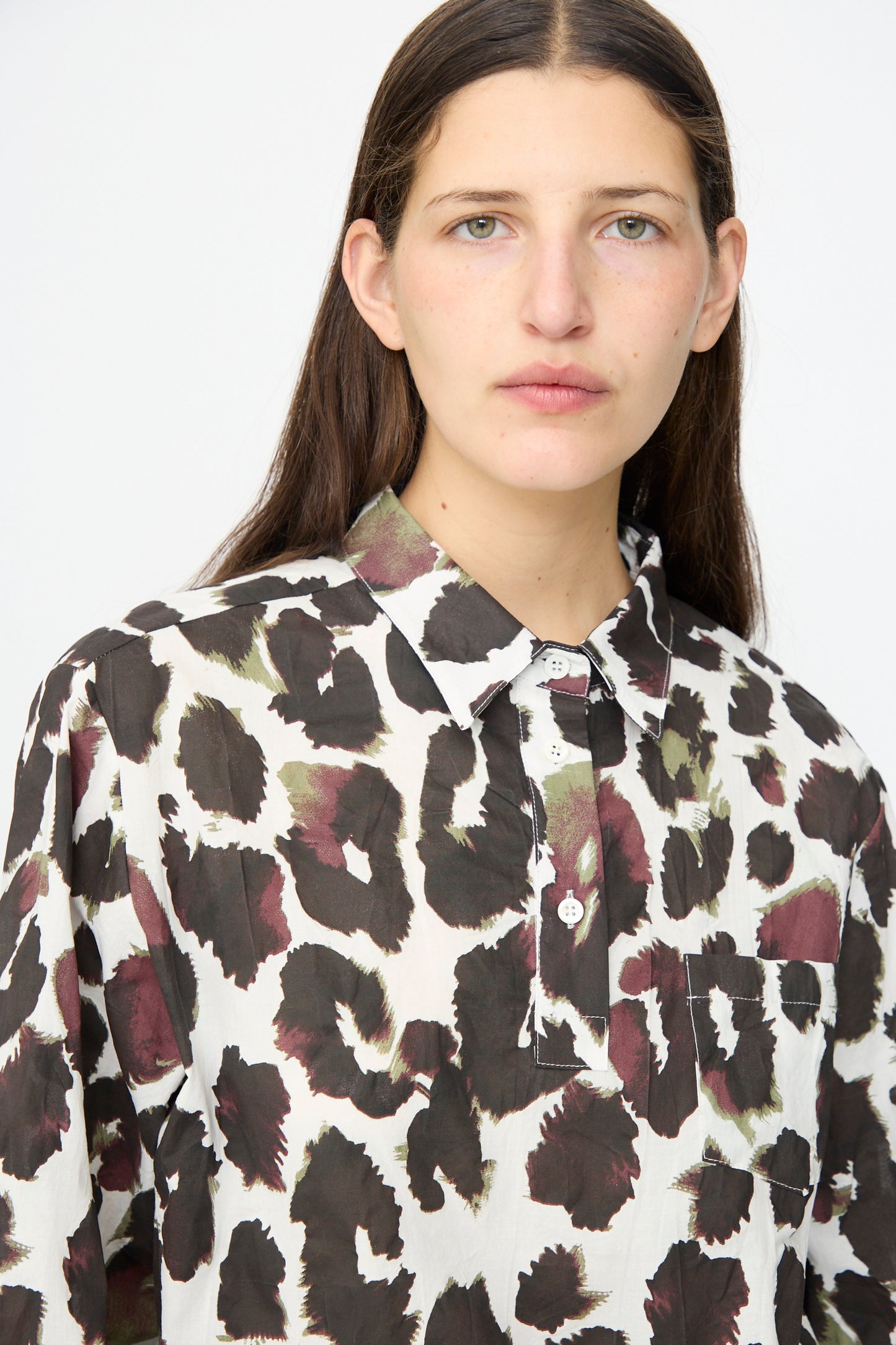 A person with long brown hair wears the AVN Joyeux Top in White with Print, which features a 3/4 sleeve and abstract black, brown, and olive spotted pattern, standing against a plain white background.