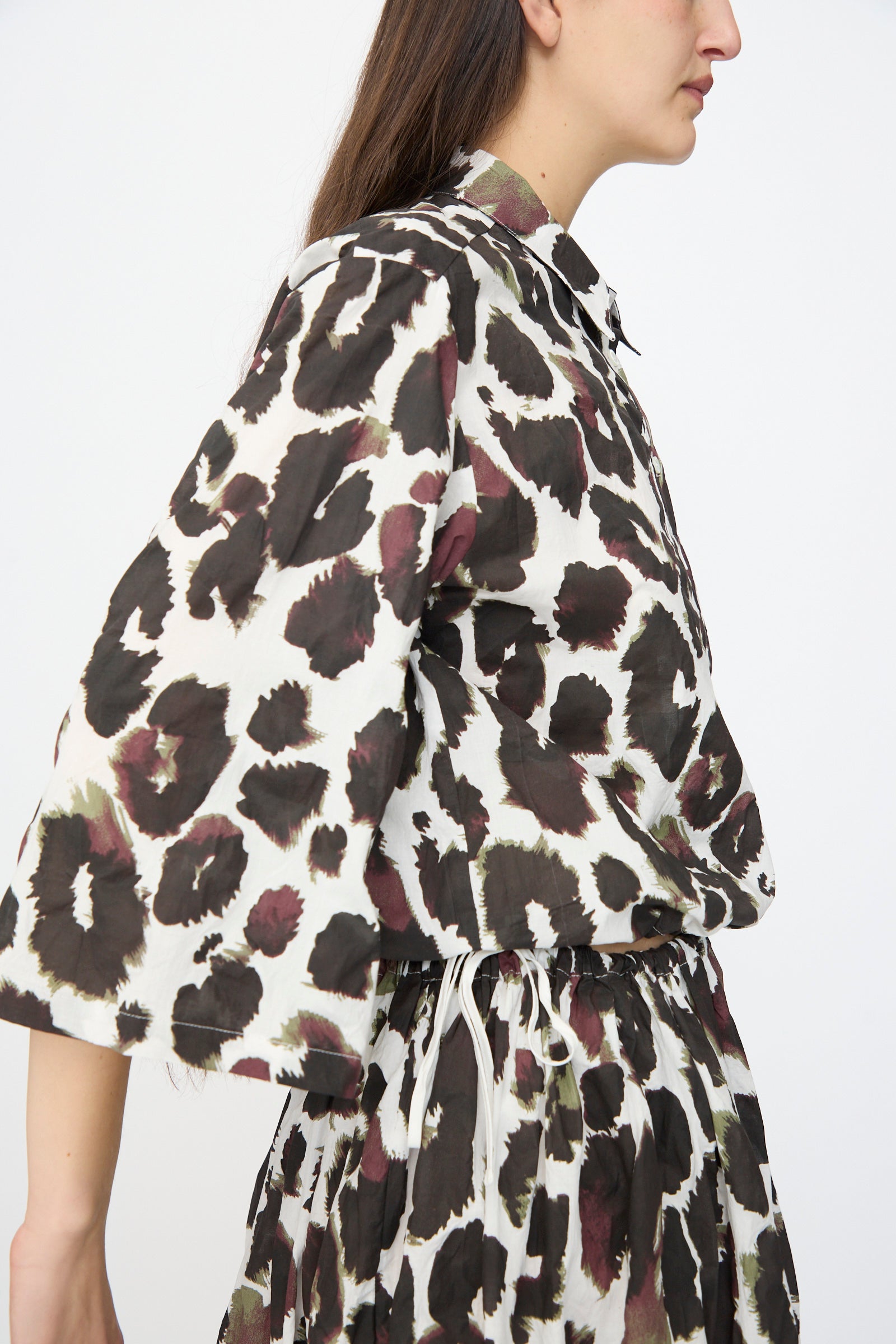 Wearing the AVN Joyeux Top in White with Print, a person is photographed from the side against a plain background.