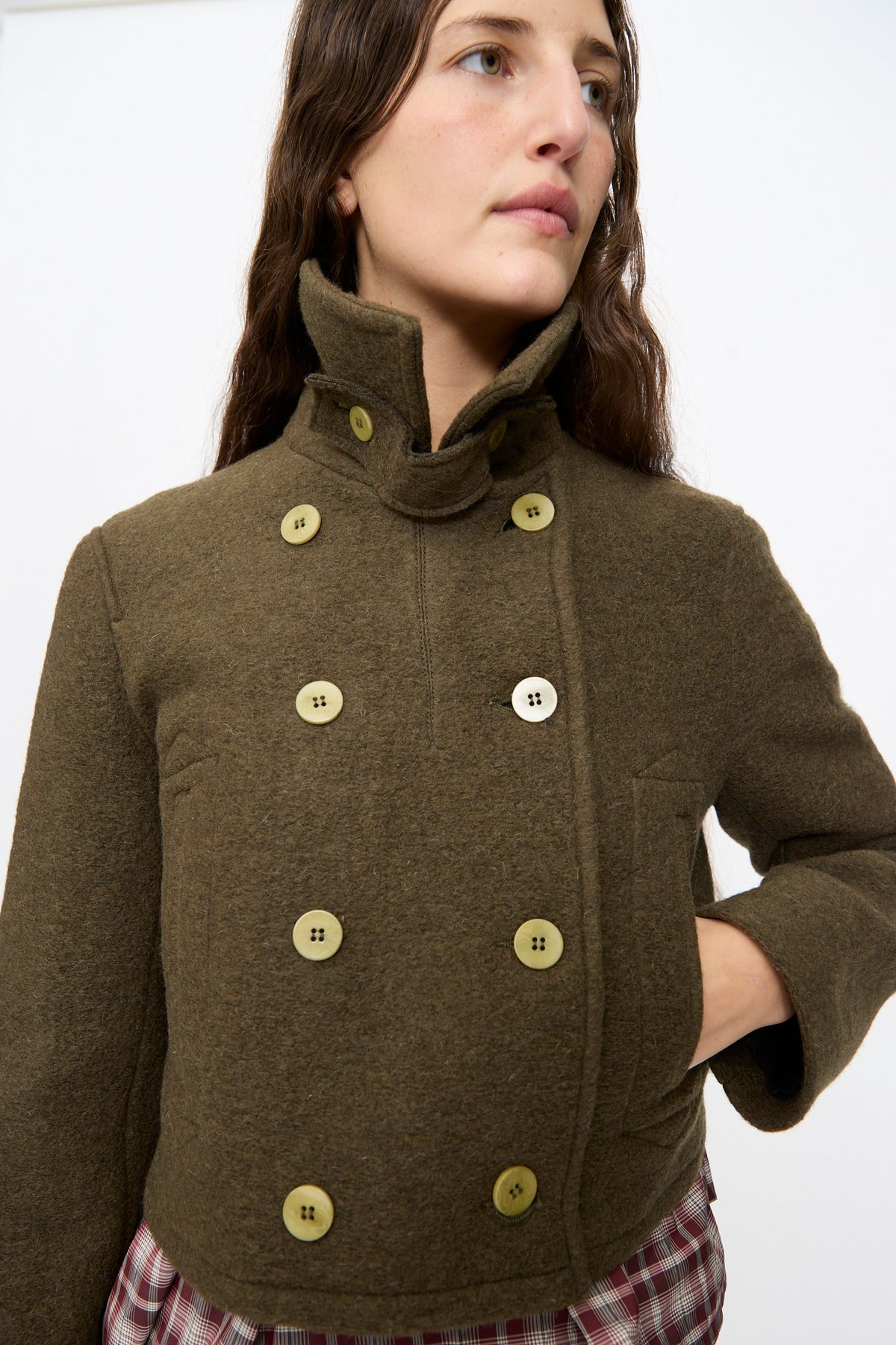 Person wearing an olive-green Mini Peacoat in Khaki, a wool blend cropped peacoat with light-colored buttons.