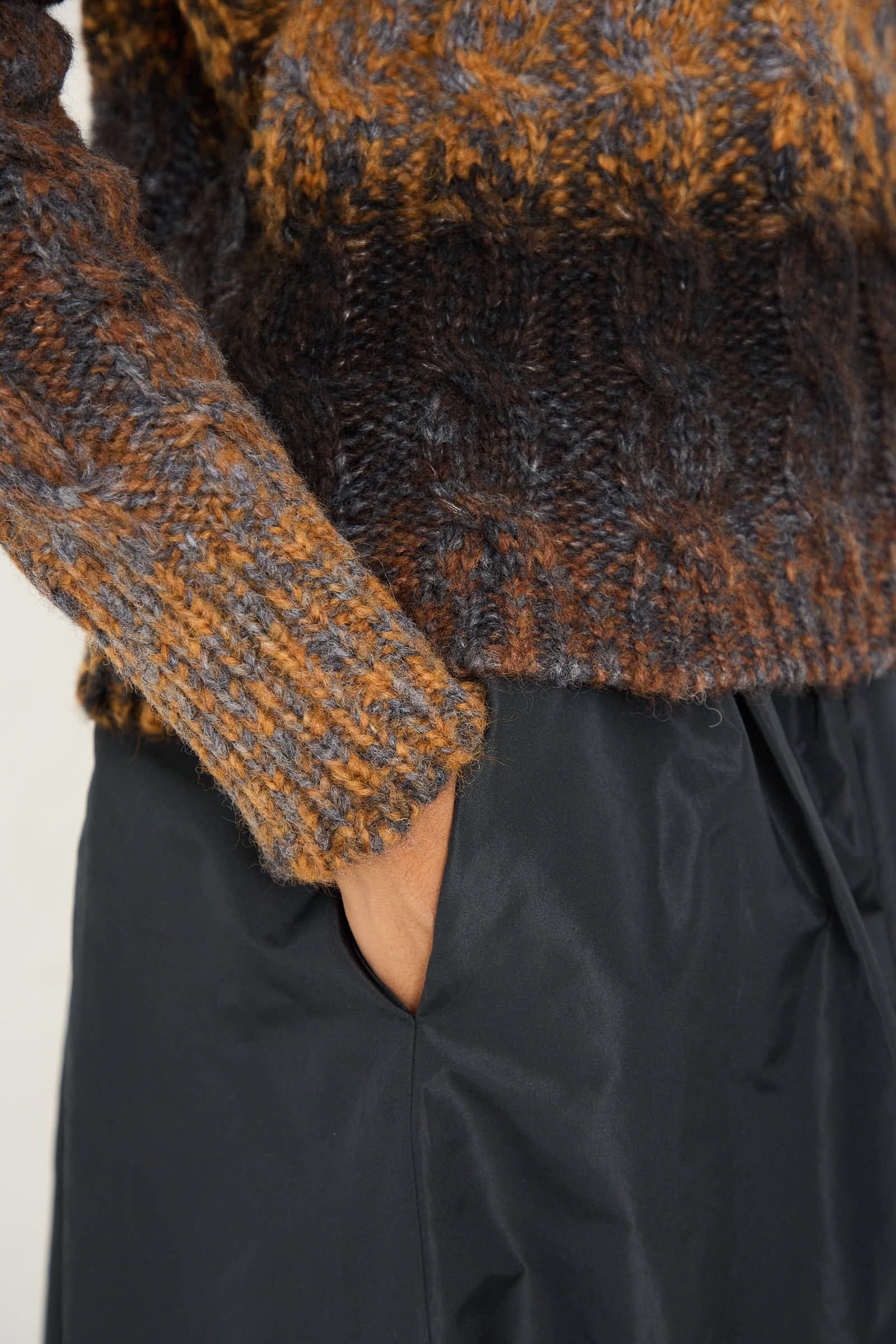 Close-up of a person wearing the AVN Mountain Sweater in Brown Melange with a hand in the pocket of dark, relaxed fit pants.