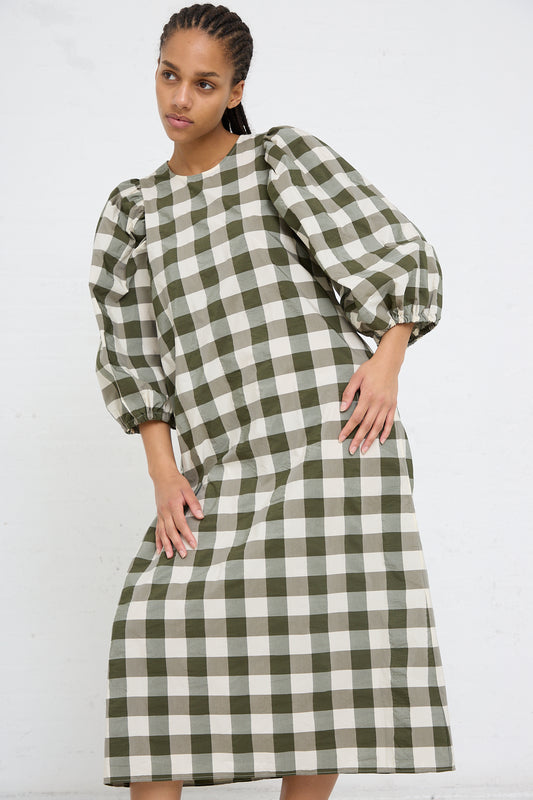 A woman in an AVN Oblo Dress in Military Green Check standing against a white background.