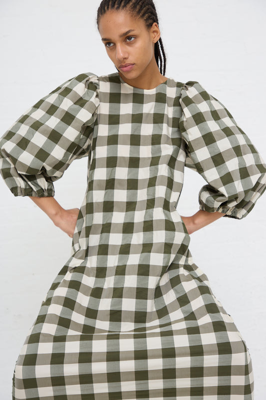Woman in an AVN Oblo Dress in Military Green Check midi dress made from a cotton polyester blend, posing with her hands on her hips against a white background.