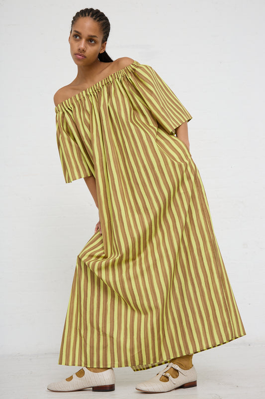A woman modeling an AVN Summer Dress in Brown and Yellow Stripes with oversized short sleeves, paired with white shoes against a plain background.