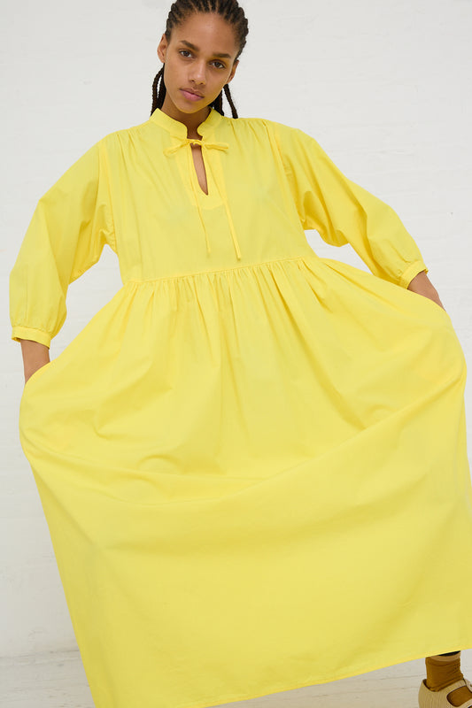 Woman posing in the AVN Sunshine Dress in Yellow, a bright yellow lightweight cotton maxi dress with puff sleeves and a keyhole neckline.