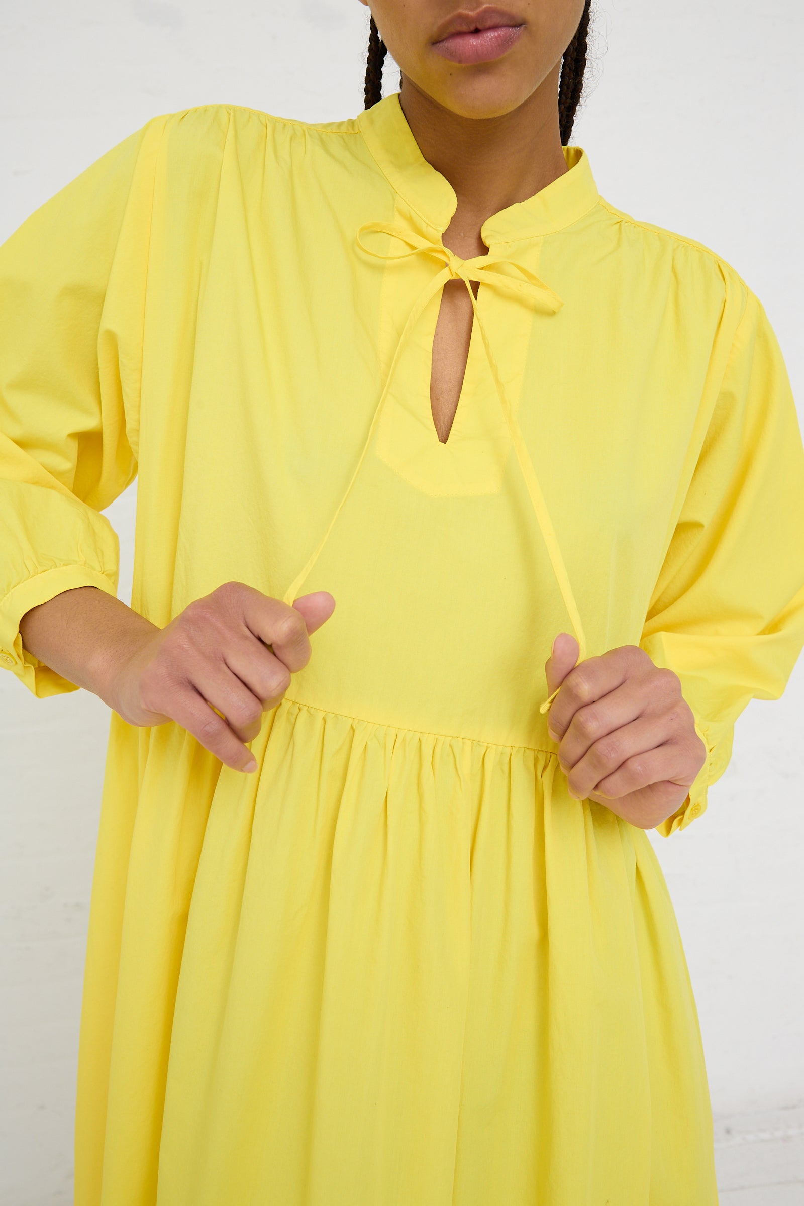 Person in a AVN Sunshine Dress in Yellow, a lightweight cotton maxi dress with a keyhole neckline and tie detail.