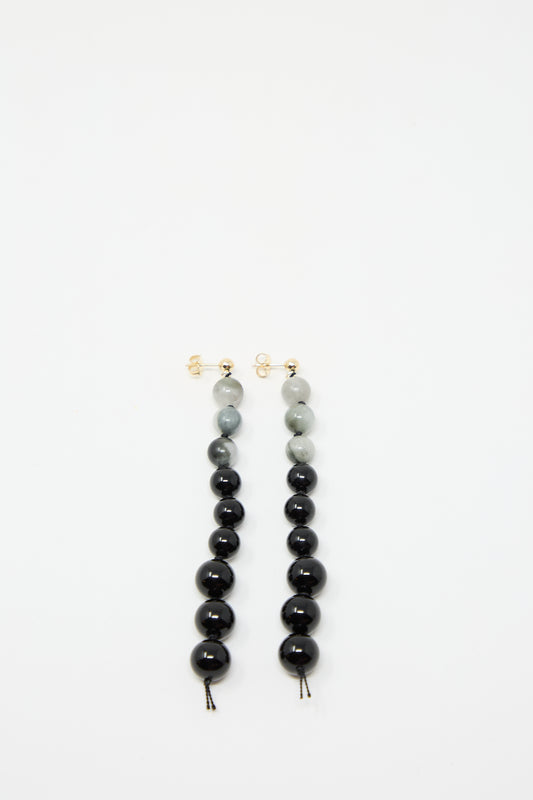 A pair of Gold Filled Beaded Earrings in White Eagles Eye and Black Onyx, featuring beads laid out on a white background, from Abby Carnevale.