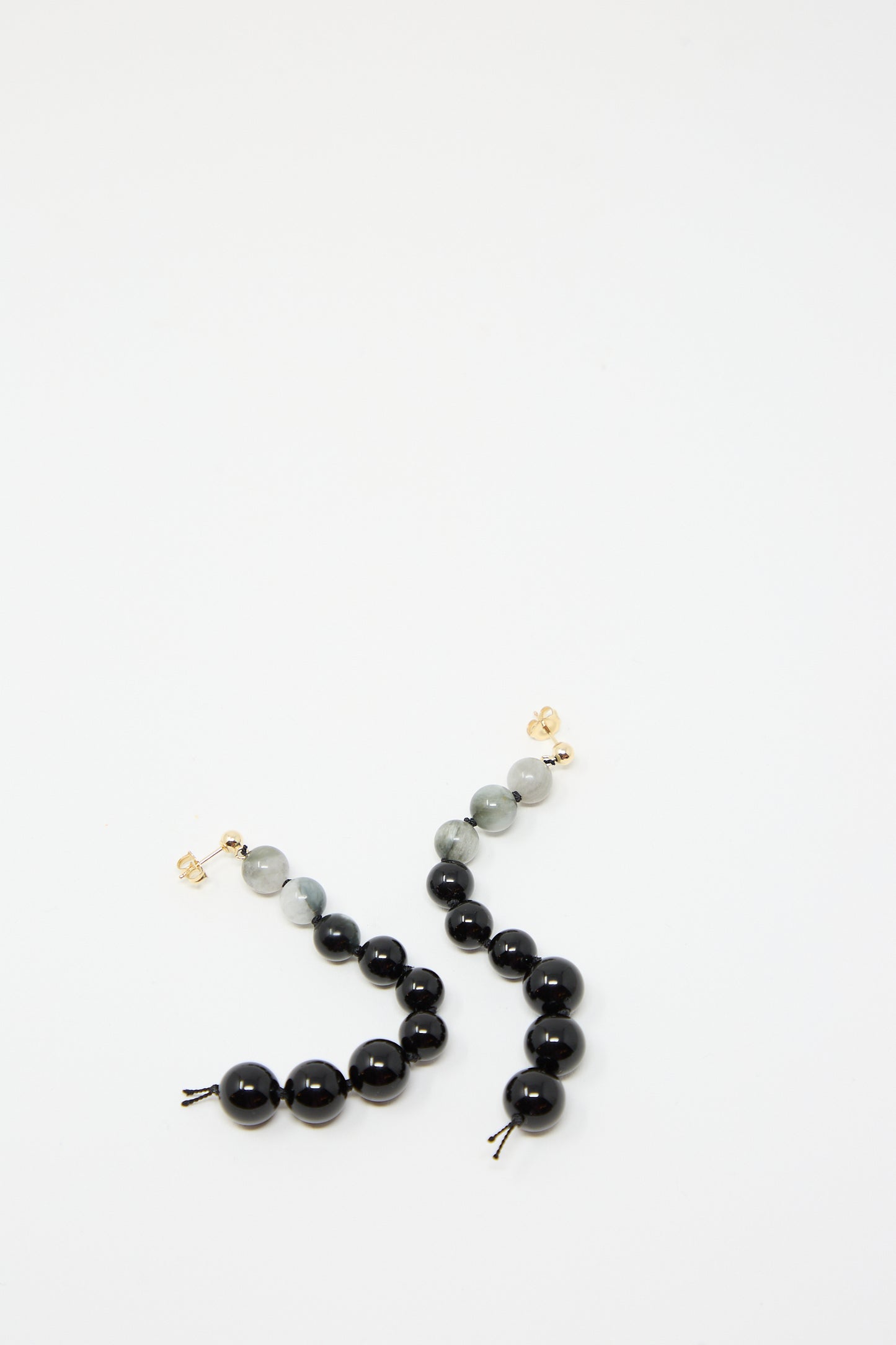 A pair of Gold Filled Beaded Earrings in White Eagles Eye and Black Onyx by Abby Carnevale lay on a white surface.